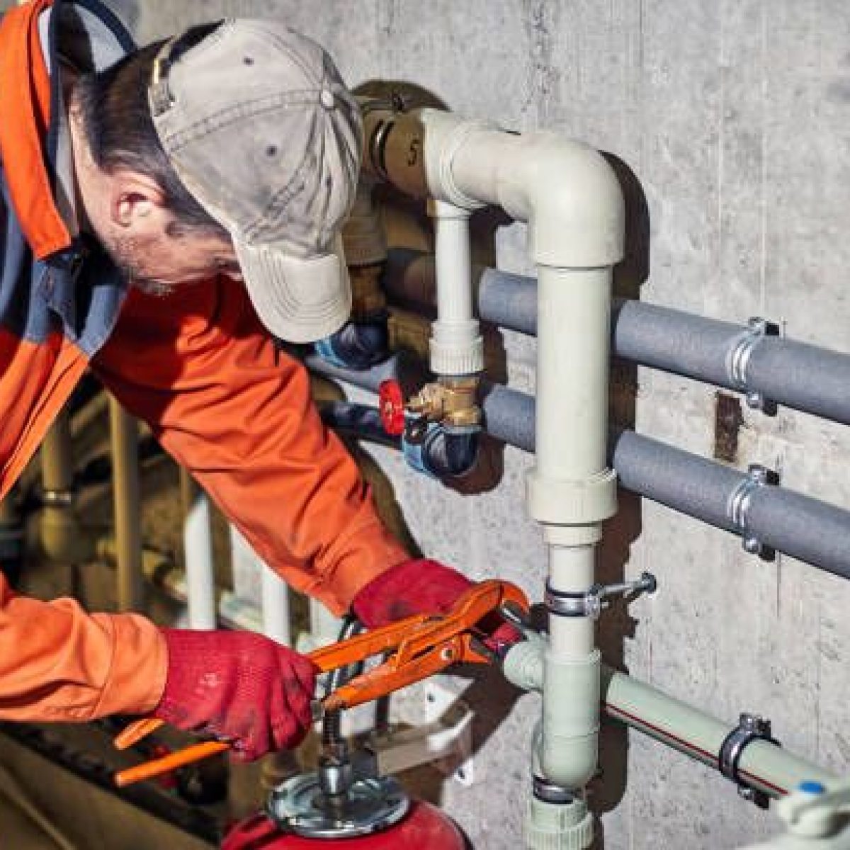 Plumber worker repairs the heating system in the house.